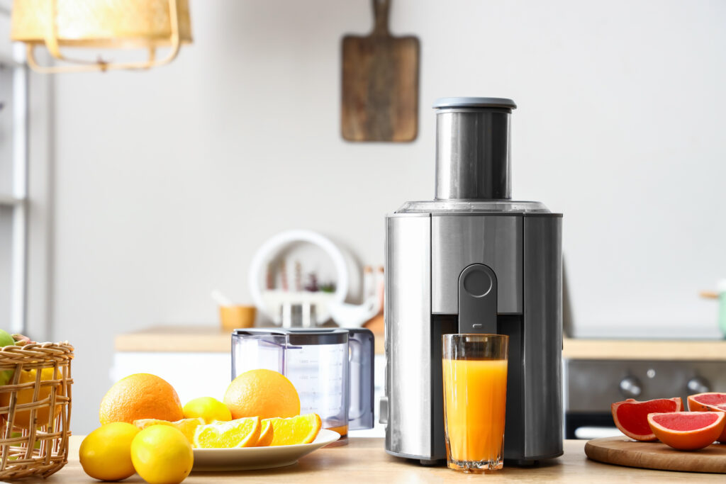 Entsafter mit frischen Zitrusfrüchten und Glas mit frischem Saft